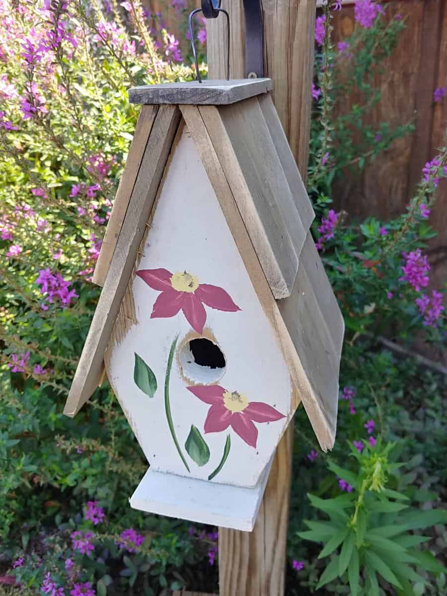 A Framed Bird House with Hand-Painted flowers and Wood Roof