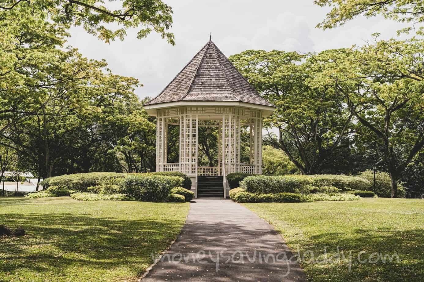 A picturesque gazebo surrounded by lush greenery in a tranquil summer park setting.