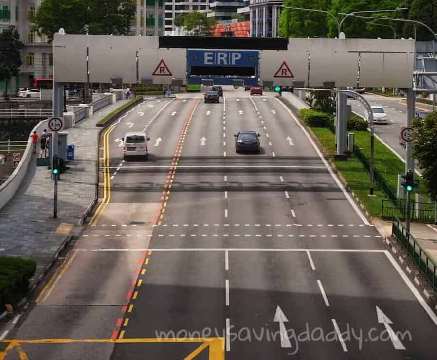 Busy roadway with Electronic Road Pricing gantry in downtown Singapore, showcasing urban architecture.