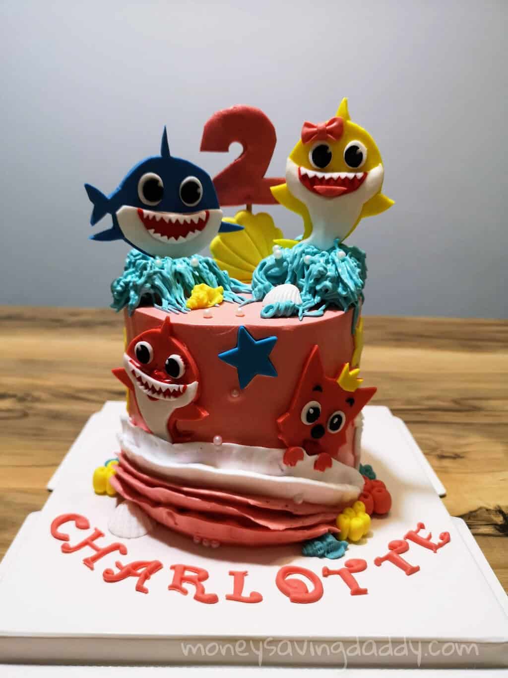 Colorful shark and star-themed birthday cake with cartoon characters for a child's celebration.