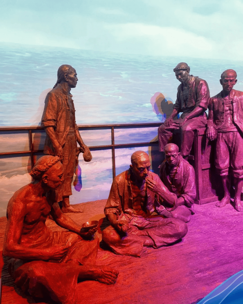Statues of early Taishanese emigrants in transit on an ocean vessel, depicting thin and weary travelers.