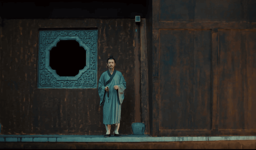 Depiction of Emperor Xiao Yan dressed in monk's robes, standing solemnly in front of a traditional structure.