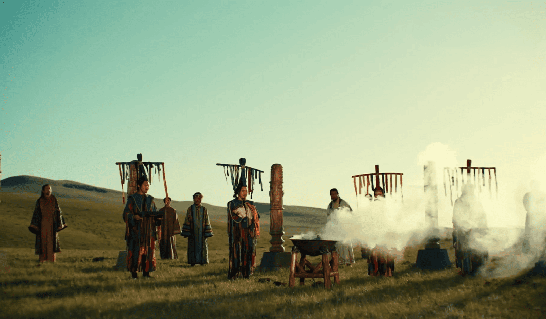 Xianbei people in traditional attire gathered in a misty field, performing a ceremonial ritual with banners and totems in the background.