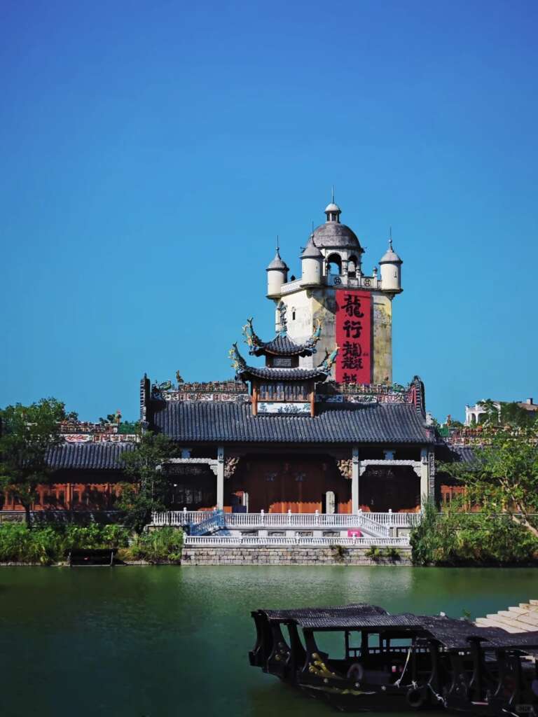 Kaiping Diaolou and traditional Chinese building by the river under a clear blue sky.
