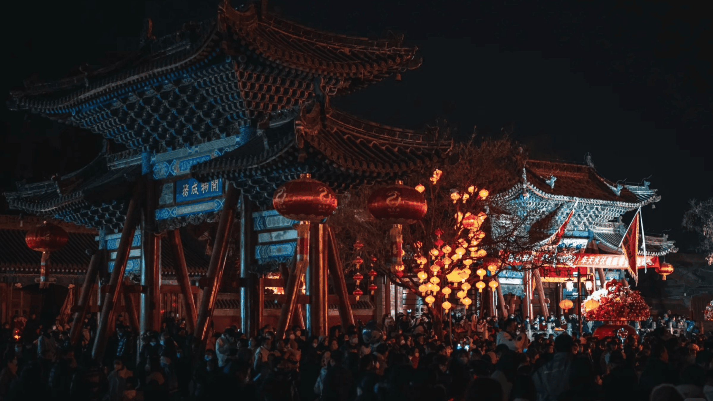 Nighttime temple gathering with lanterns and crowds during modern ancestor worship practices