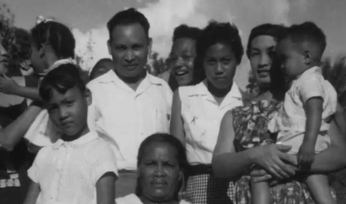 A mid-20th-century photograph showing a Chinese Jamaican family, including parents, children, and extended relatives, gathered outdoors.