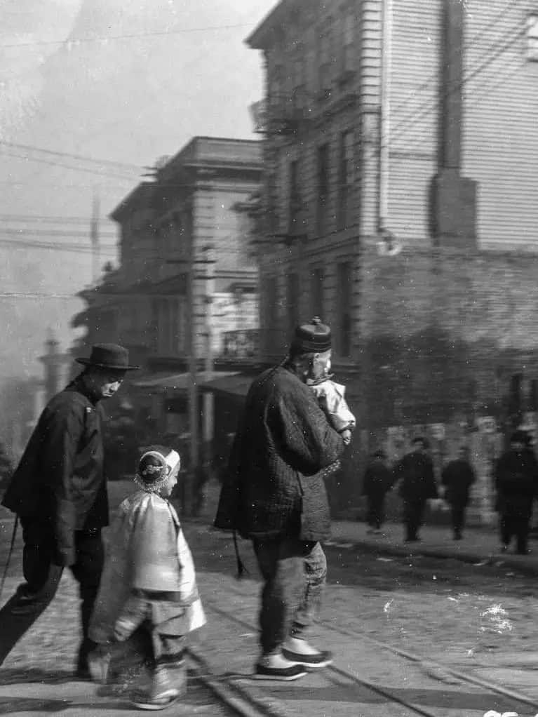 A historical photograph of a Wuyi migrant family walking through San Francisco’s Chinatown, symbolizing cultural resilience and community life.