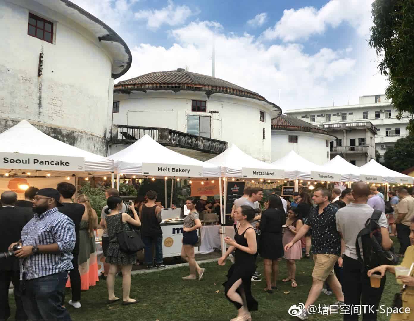 A bustling outdoor market with food stalls like Seoul Pancake and Melt Bakery at The Granary Restaurant in Kaiping Tangkou, featuring historic diaolou watchtowers in the background.