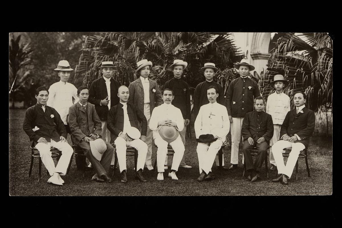 Historical photo of Sun Yat-Sen seated with fellow revolutionaries in Singapore, strategizing to overthrow the Qing Dynasty during the early 20th century.