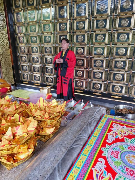 Taoist priest Mr. Wu performing a solemn ritual inside a temple adorned with intricate decorations.