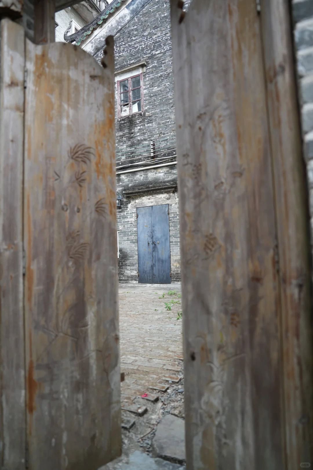 View through wooden doors into courtyard of an old home in rural China