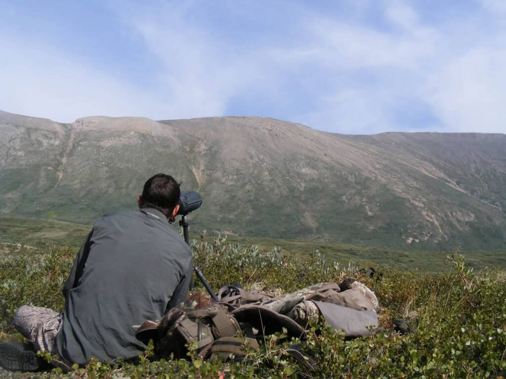 Scenic mountain landscape with a hiker using binoculars near Scoop Lake Outfitters.