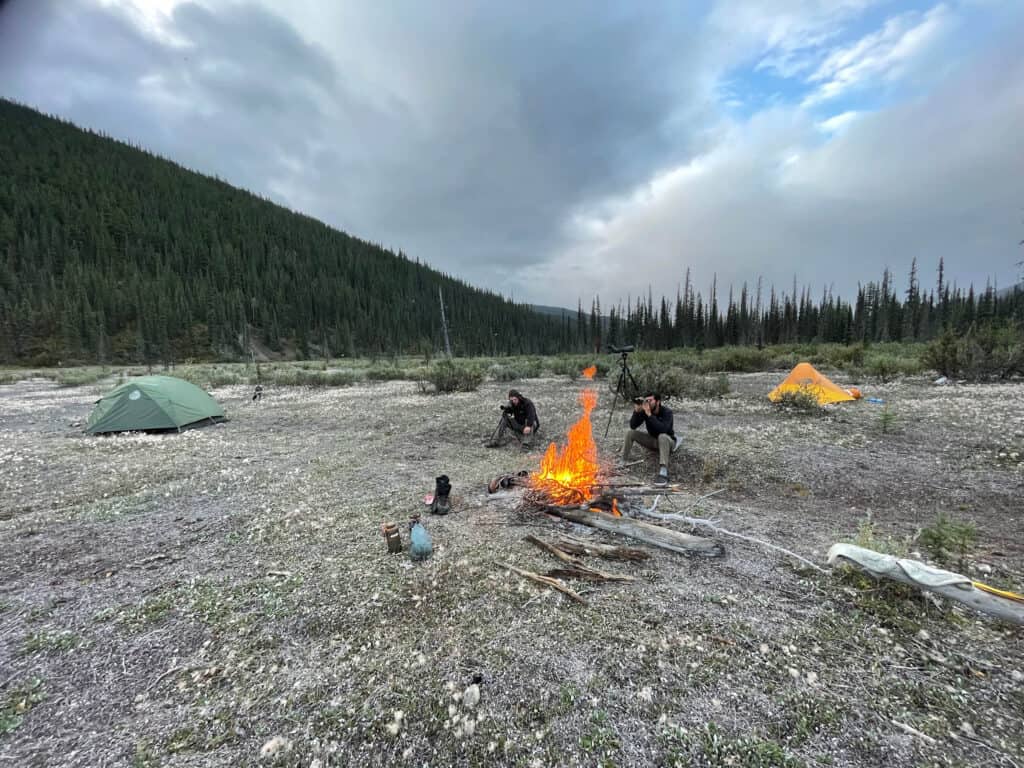 Beautiful outdoor camping scene at Scoop Lake Outfitters with tents, fire, and mountain backdrop.