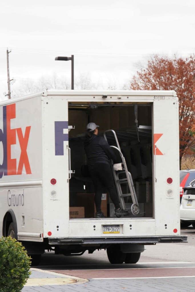 FedEx truck with a worker unloading packages, representing that FedEx does not transport household pets like dogs and cats