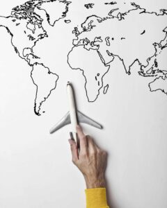 Hand holding a toy airplane over a world map illustration, symbolizing international pet travel planning.
