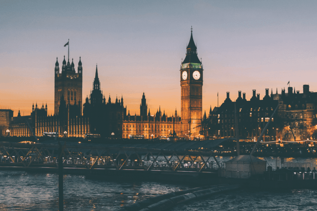 Big Ben and the Houses of Parliament illuminated at dusk, viewed across the Thames River in London.