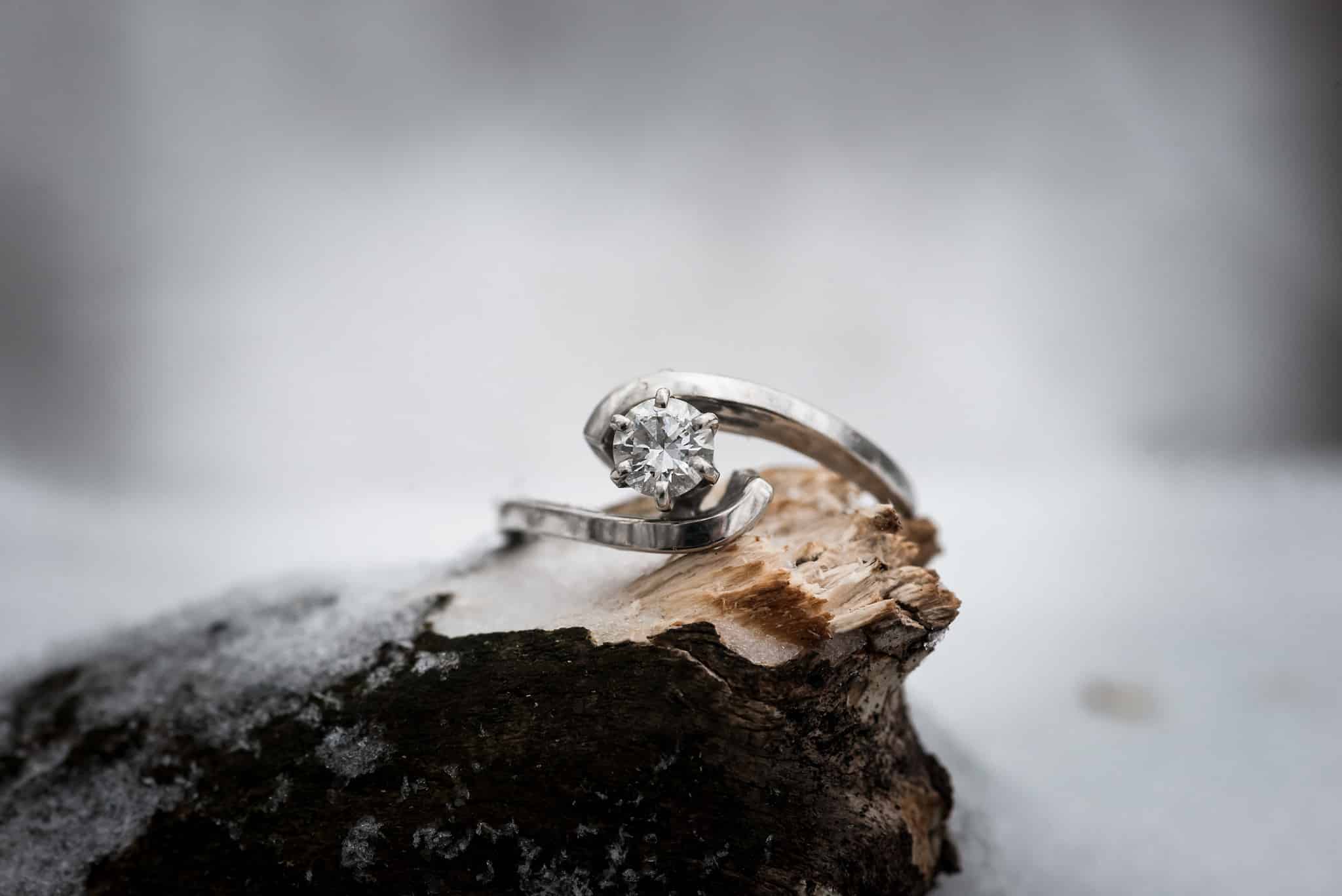 Diamond engagement ring in snow during winter engagement session in Auburn, Indiana by Kasey Wallace Photography