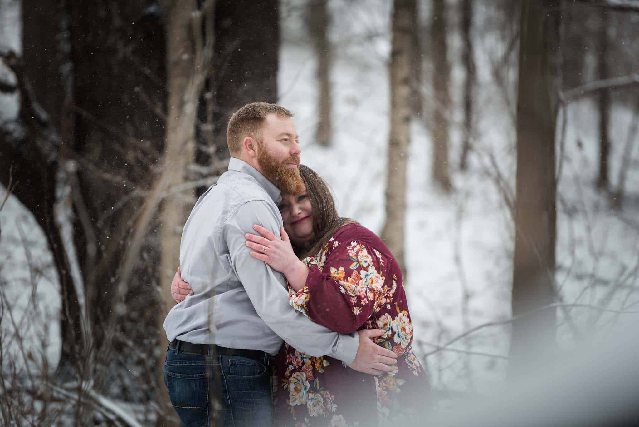 Couple embracing during snowy, wintry engagement session in Auburn, Indiana by Kasey Wallace Photography