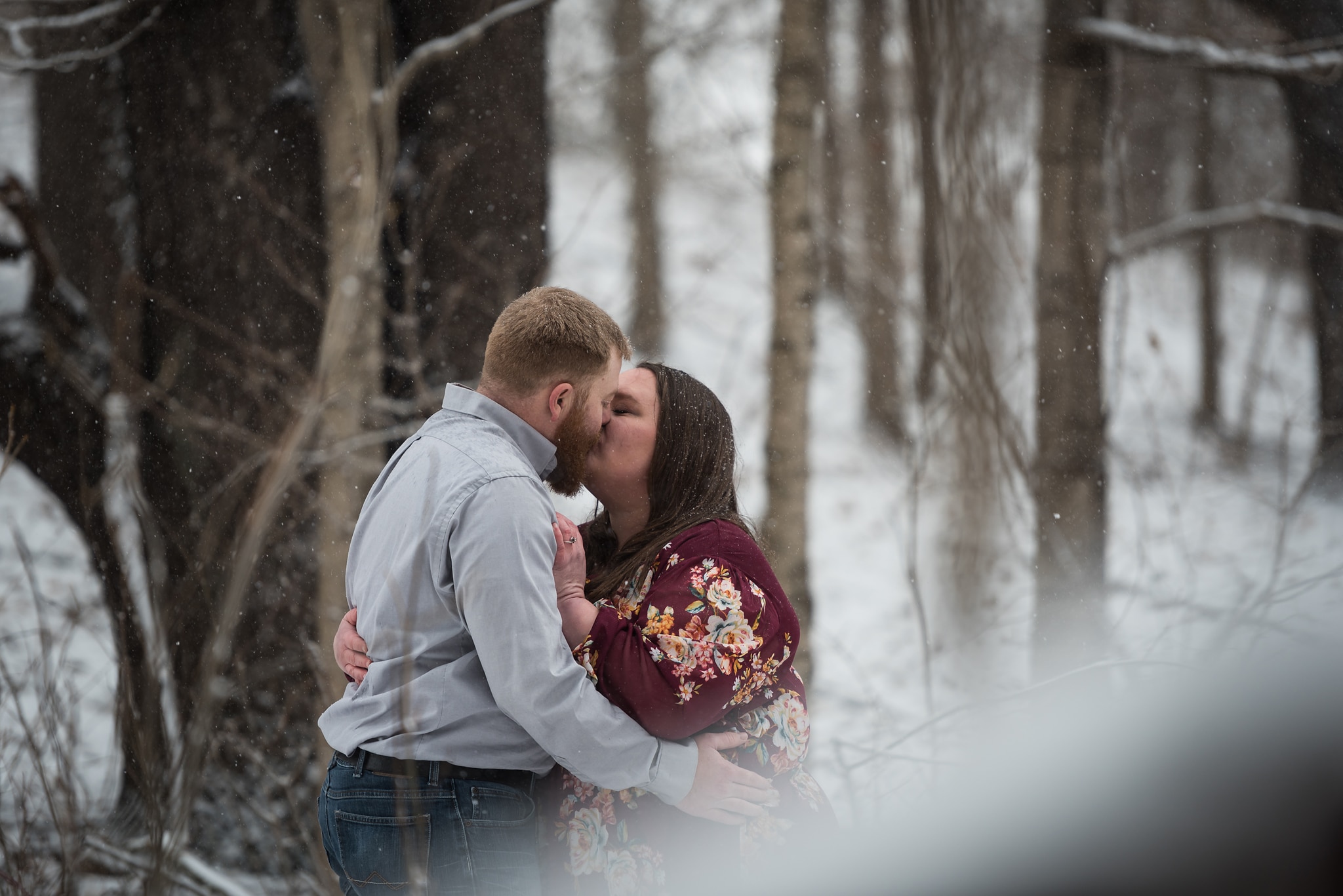 Couple embracing during snowy, wintry engagement session in Auburn, Indiana by Kasey Wallace Photography