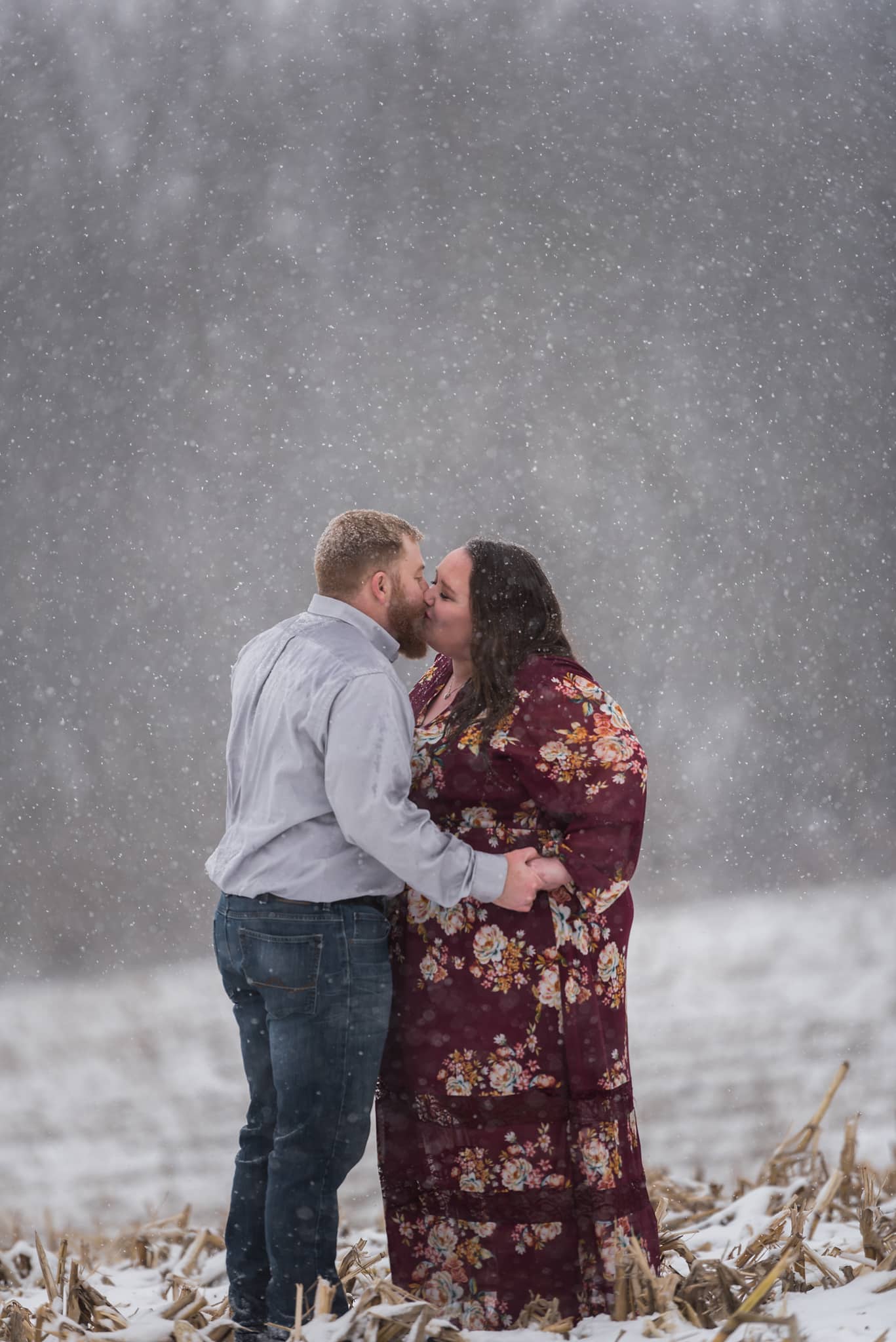 Couple embracing during snowy, wintry engagement session in Auburn, Indiana by Kasey Wallace Photography