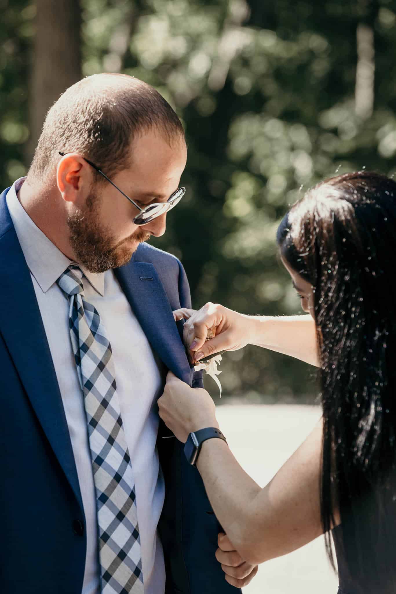 Bridesmaid pinning boutonnière on groom prior to wedding ceremony at Pokagon State Park