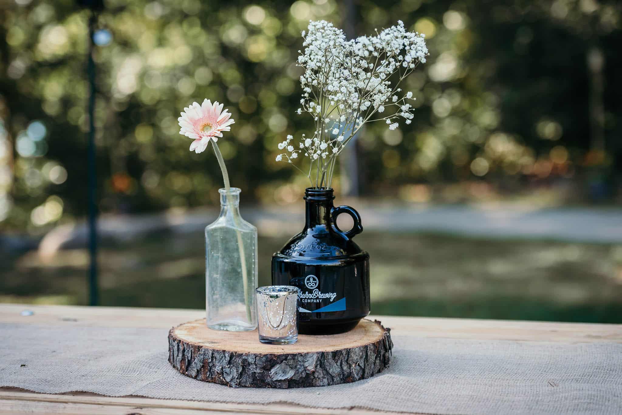 Unique outdoor DIY wedding centerpieces with fresh flowers and jug from Auburn Brewing Company at Pokagon State Park