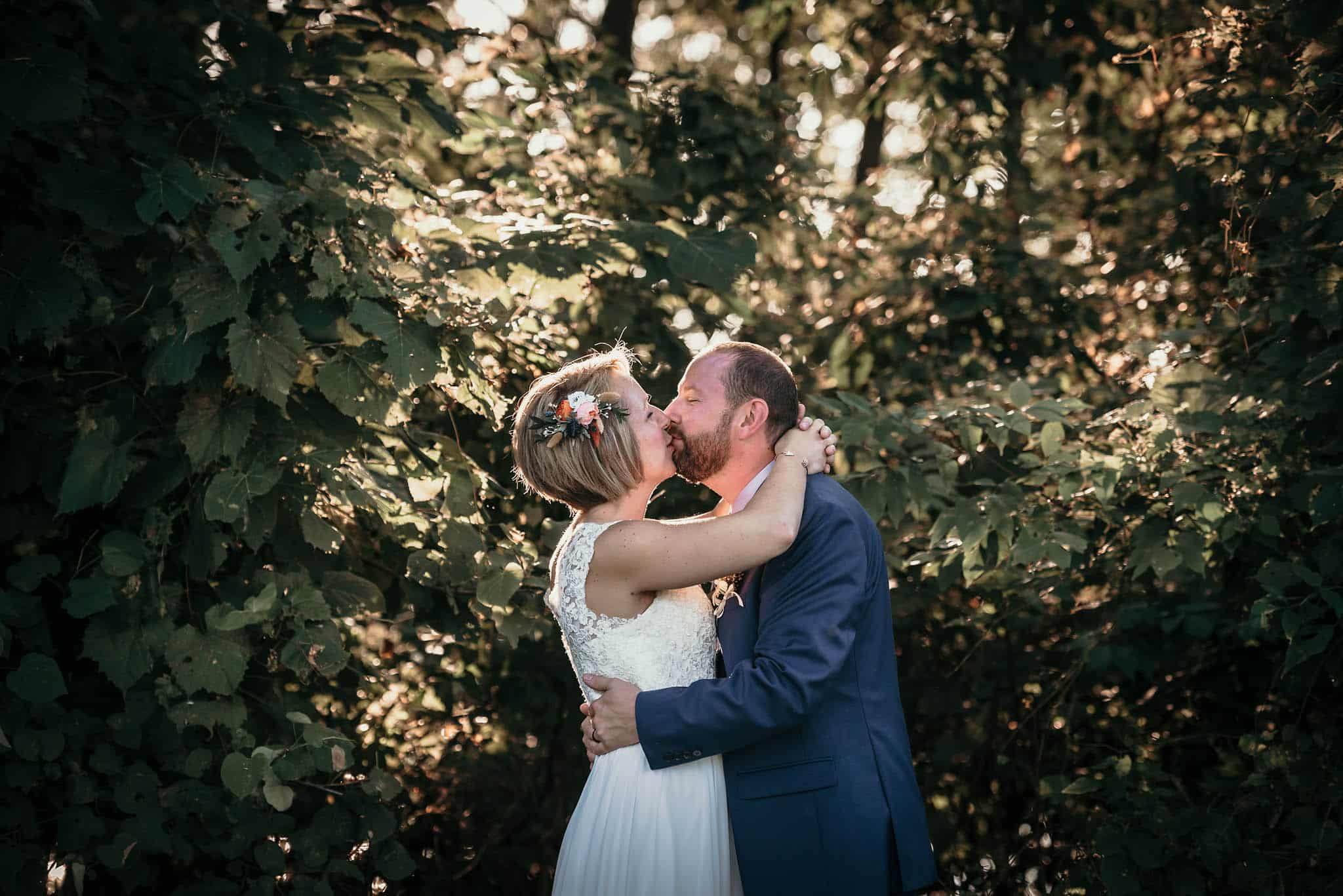 Bride and groom kissing in front of trees after unique outdoor DIY wedding at Pokagon State Park