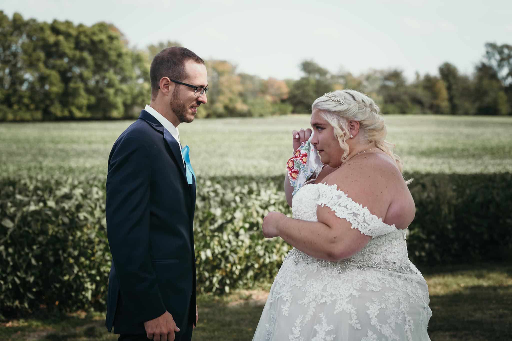 Bride wiping tears with family heirloom hand embroidered handkerchief during first look