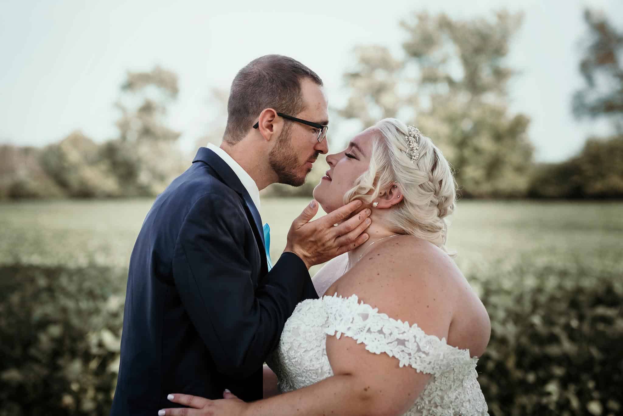 Groom gently lifting bride's chin for a kiss during a photo shoot at intimate fall wedding