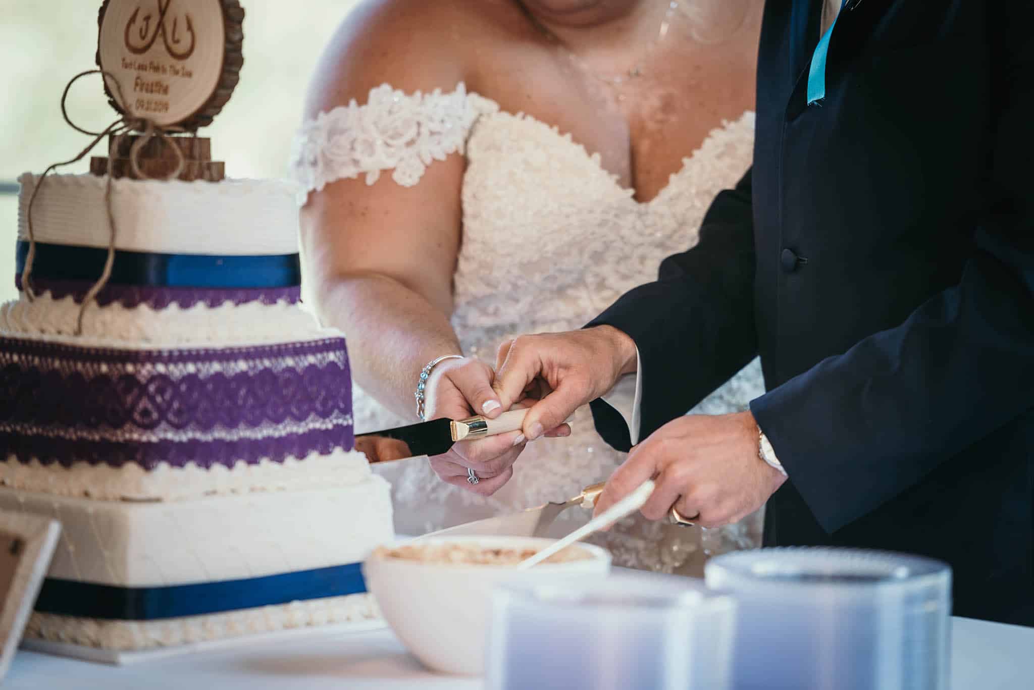 Close up of bride and groom cutting cake during reception at intimate fall wedding at the Lodge at River Valley in Yorktown, Indiana