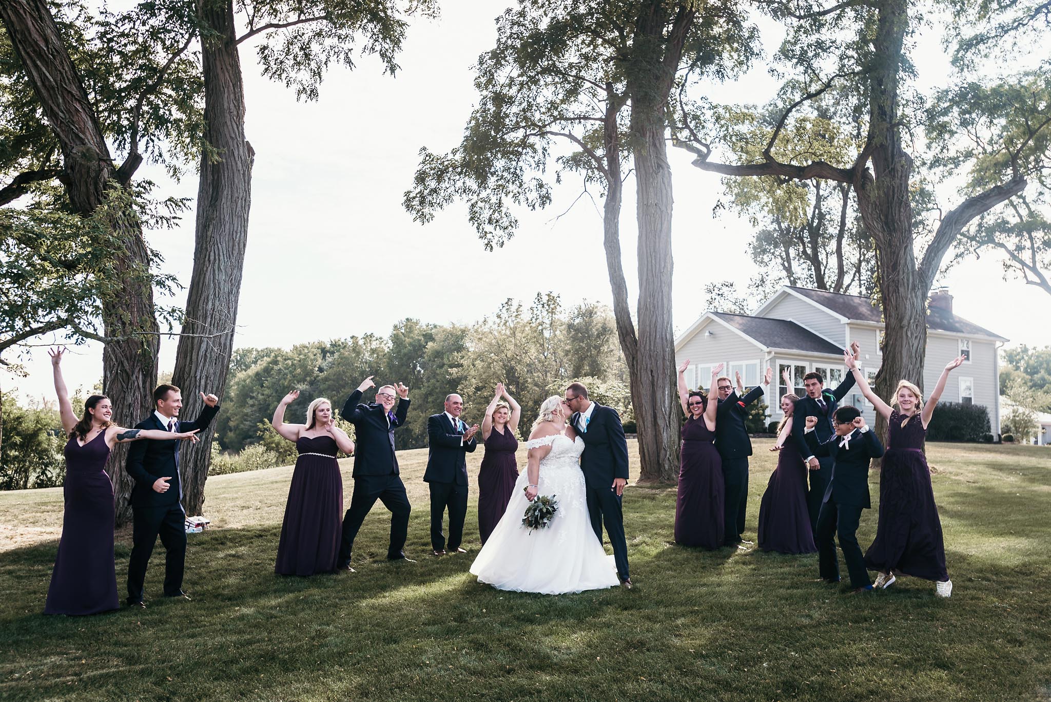 Wedding party cheering for bride and groom kissing outside during intimate fall wedding at the Lodge at River Valley in Yorktown, Indiana