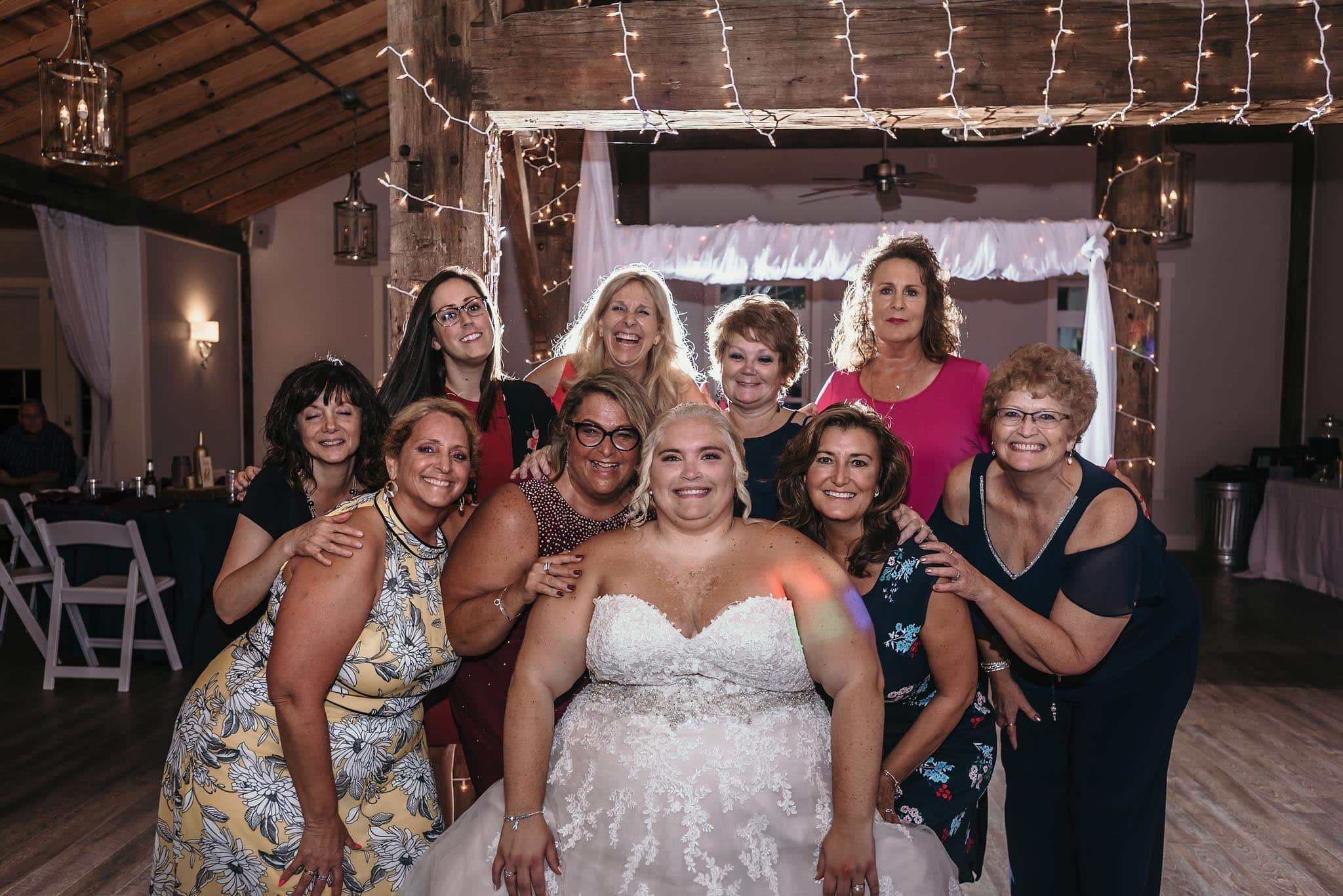 Bride posing with guests during reception of intimate fall wedding at the Lodge at River Valley in Yorktown, Indiana