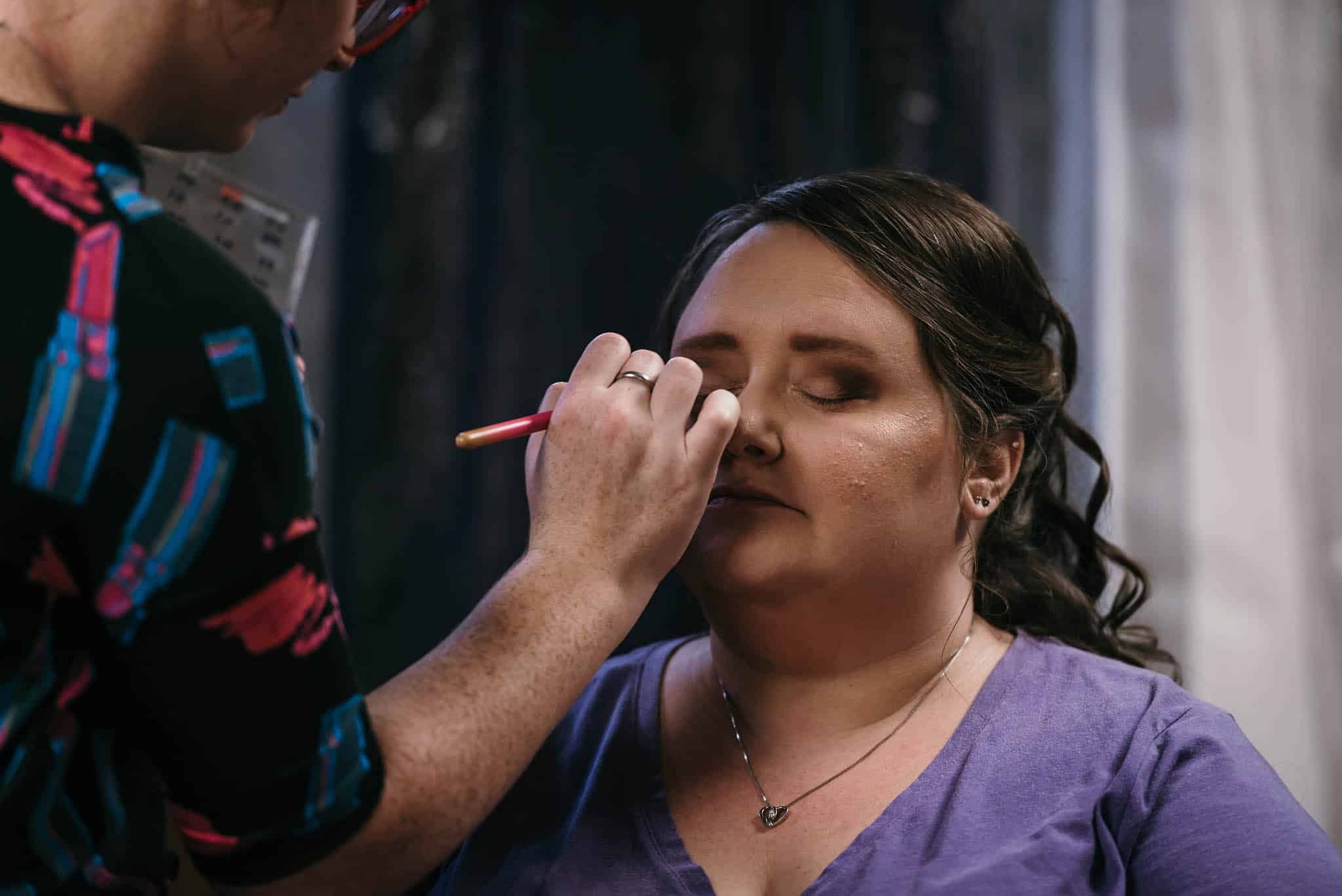 Makeup artist applying eyeshadow to bride