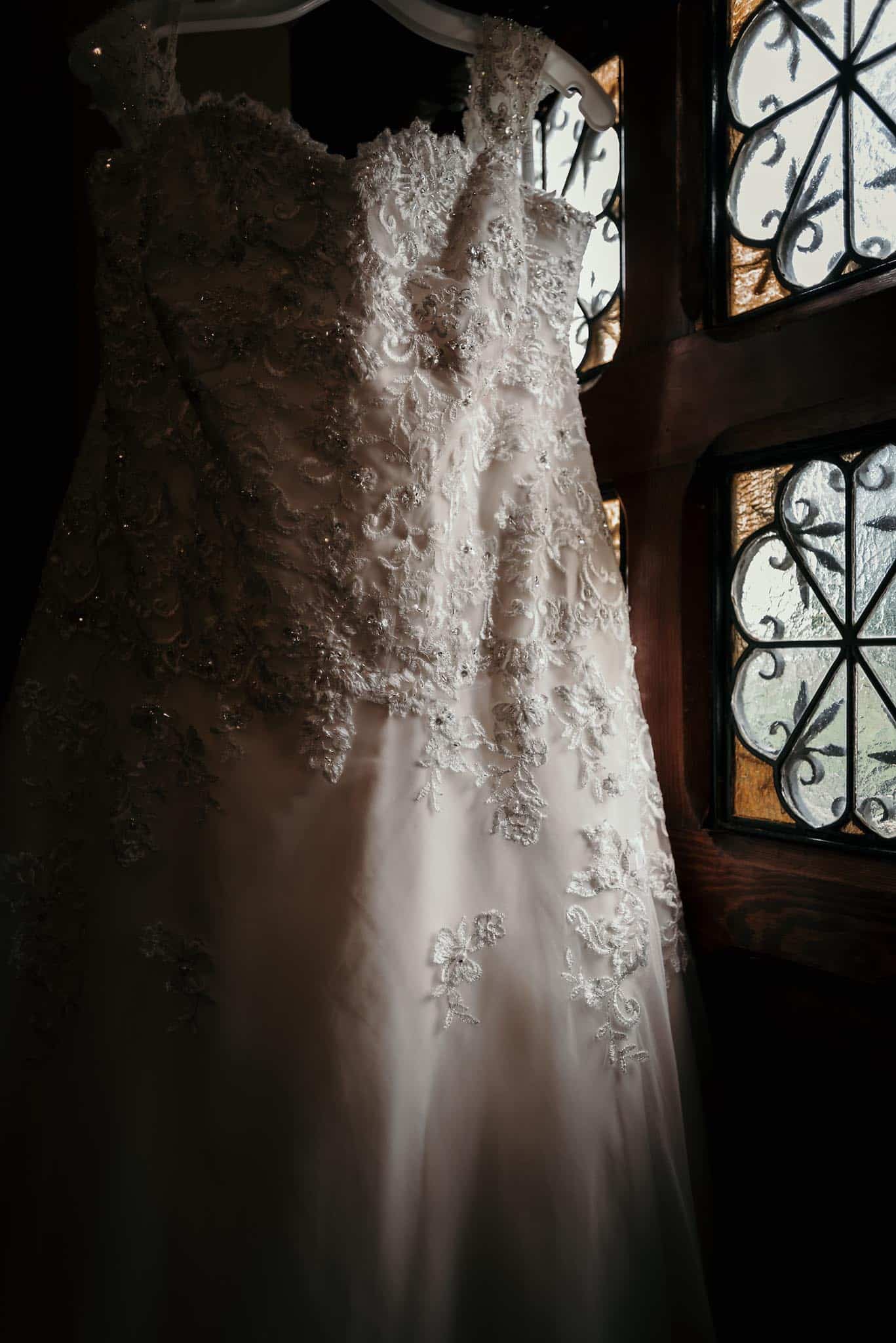 Dramatic details of wedding gown next to Catholic Church stained glass doors