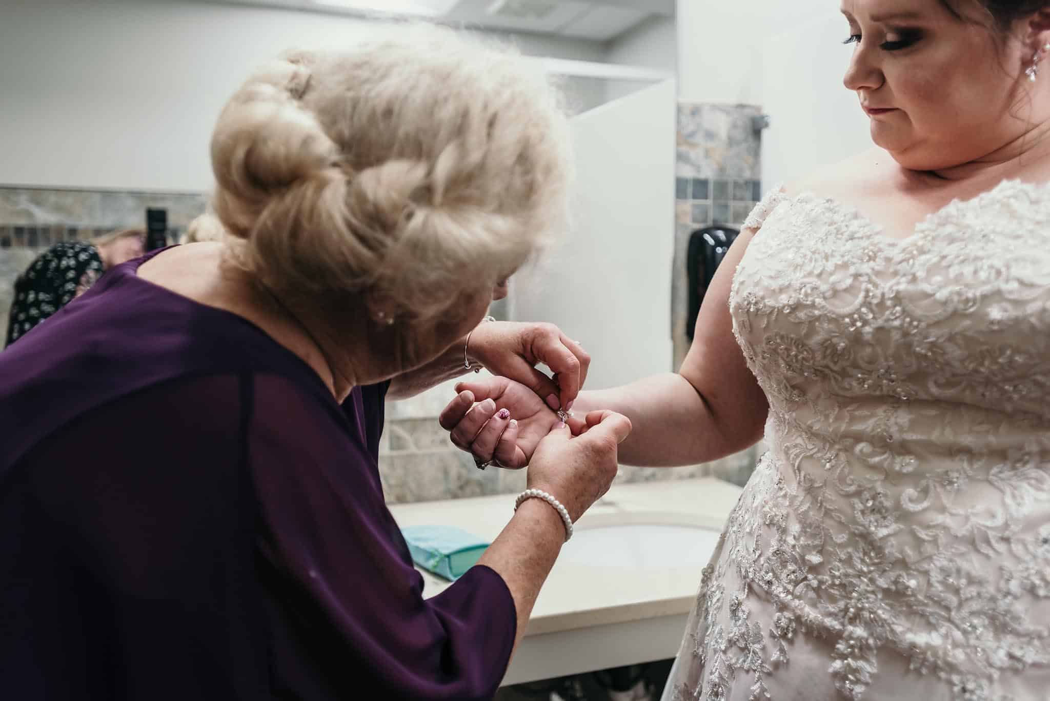 Mother of the bride clasping bracelet on bride's wrist