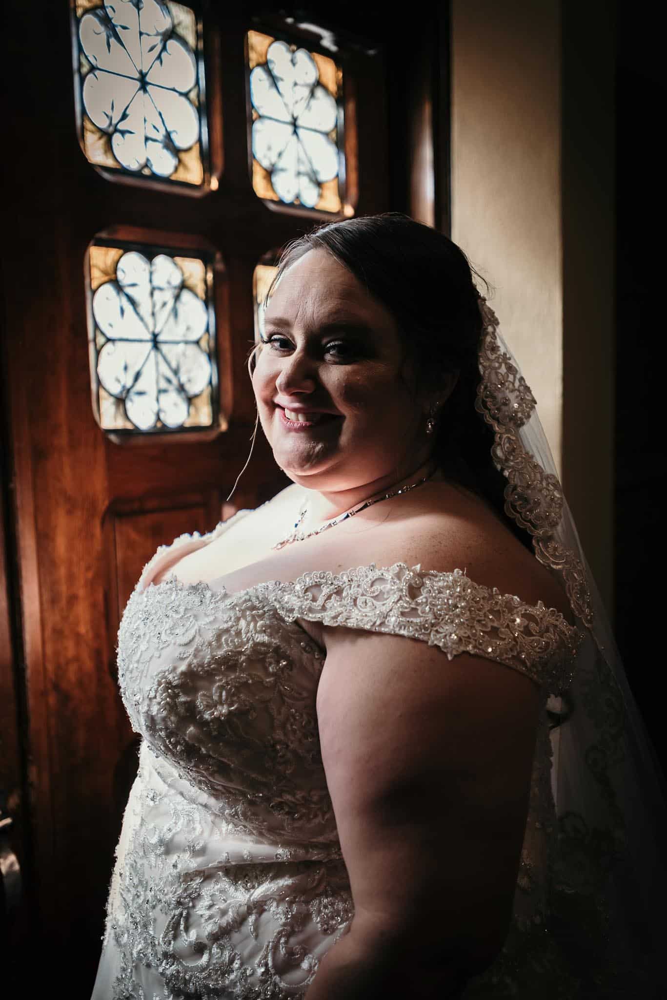 Bride looking out Catholic Church doors