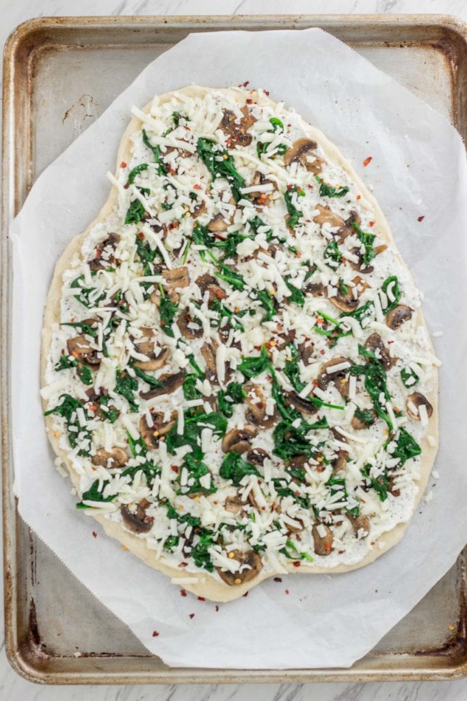 Whole white pizza on the baking sheet before baking in the oven