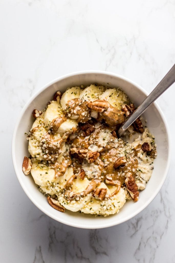 Basic overnight oats with banana slices and nut butter drizzled on top. Sprinkle of pecan pieces and hemp seeds