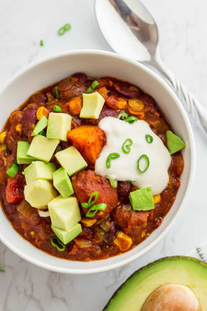 Top view of vegan butternut squash chili topped with avocado chunks and cashew cream.
