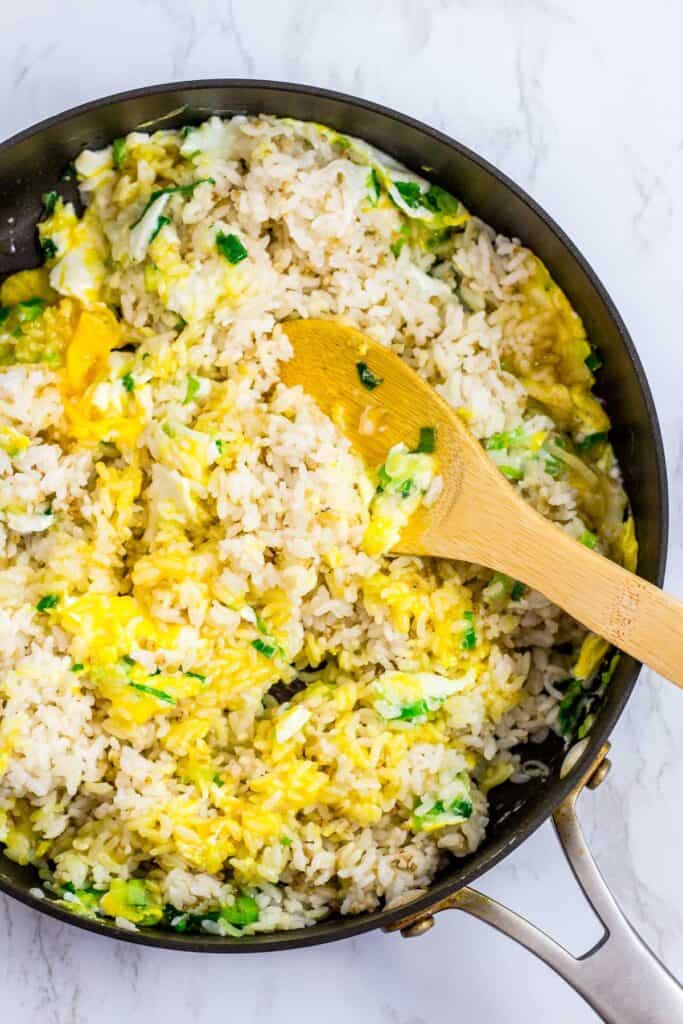 rice is just mixed in with green onion and fried eggs in the pan