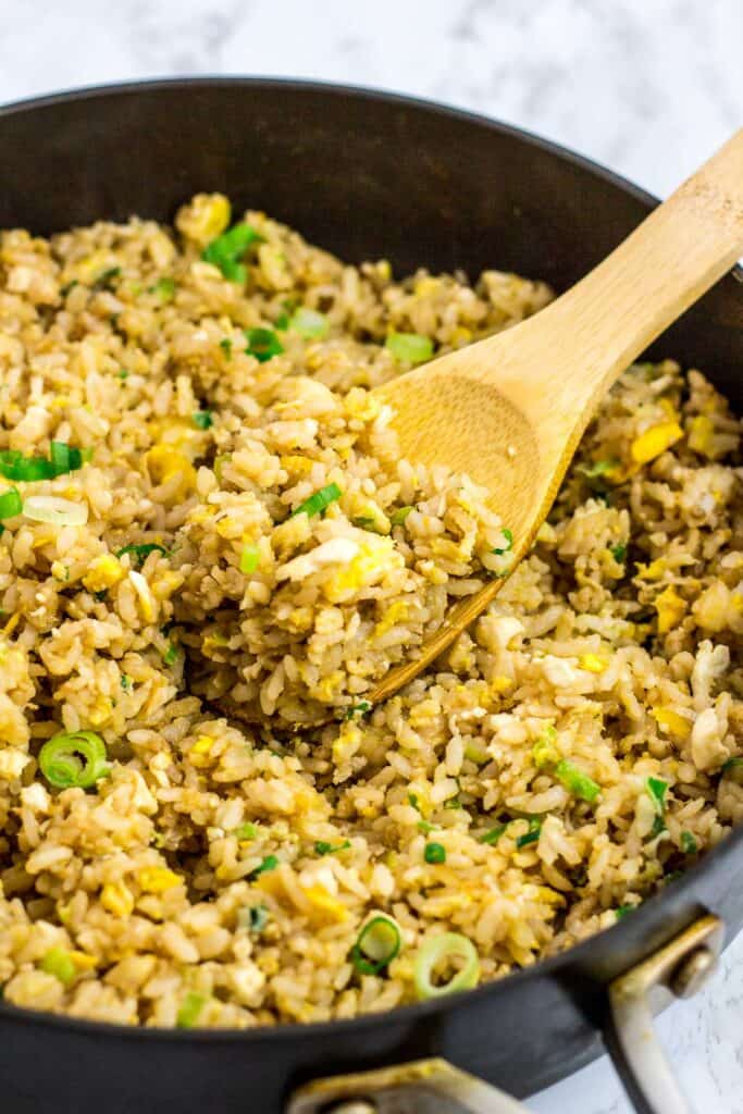 A spoonful of egg fried rice on the wooden spoon