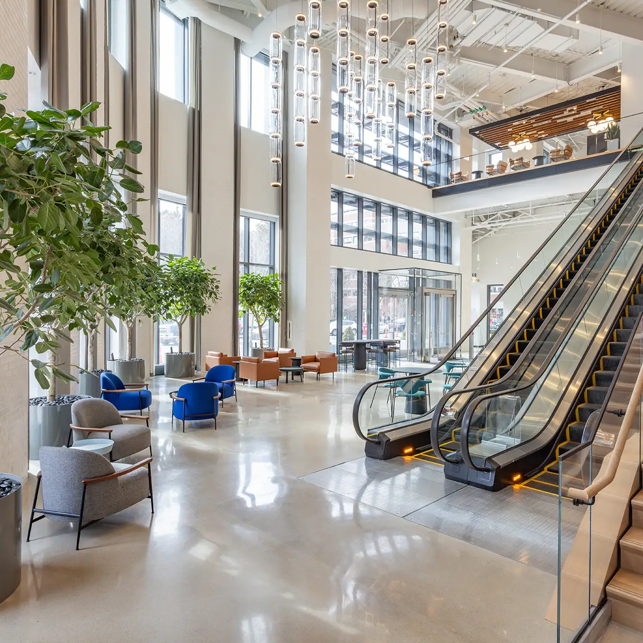 Modern lobby with large windows, seating, and escalator at CambridgeSide mall.
