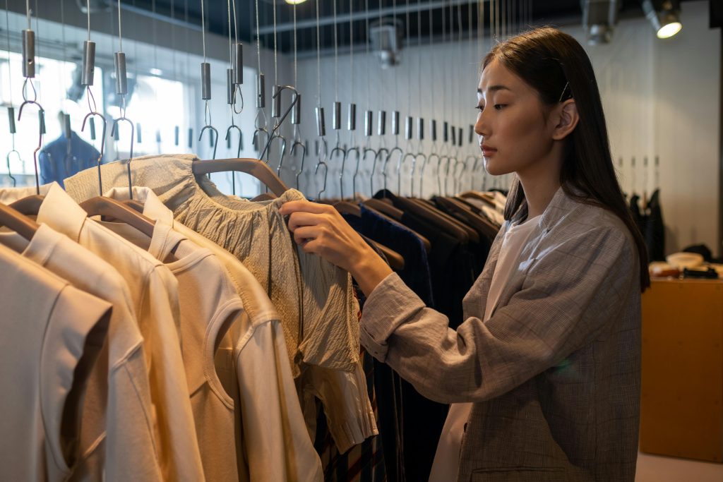 Woman browsing clothes in a crowded shop, symbolizing the challenge of standing out in a saturated fashion market