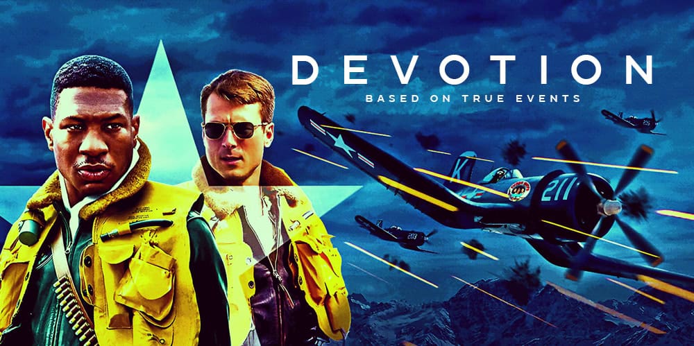 Two men in yellow jackets with fighter jets in the background for Devotion film review.