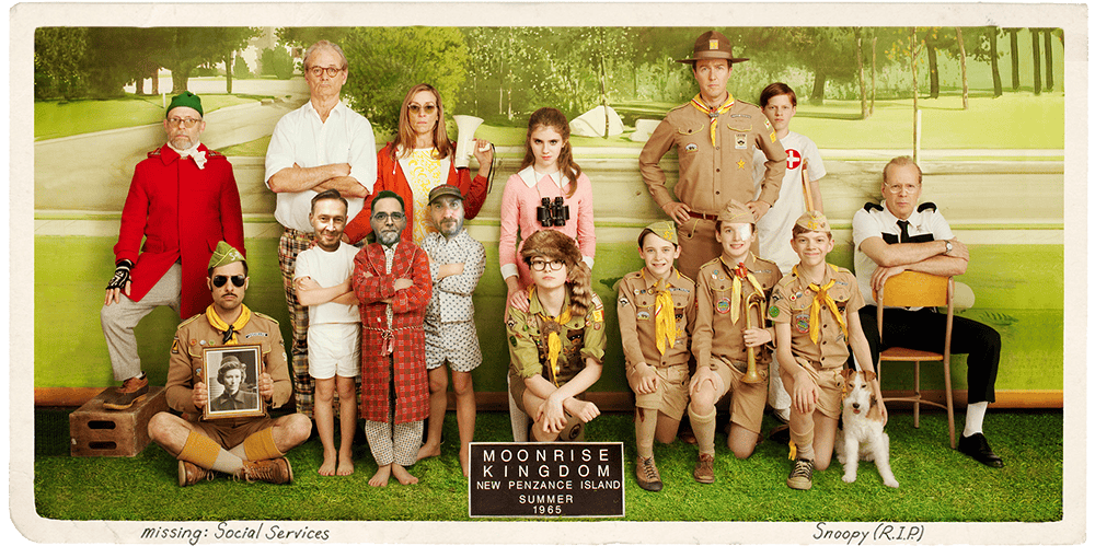 Group of people dressed in various costumes from movies, posing outdoors with a green park backgroun.