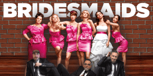Group photo of the bridesmaids from the movie "Bridesmaids" in pink dresses with a brick wall backgr.