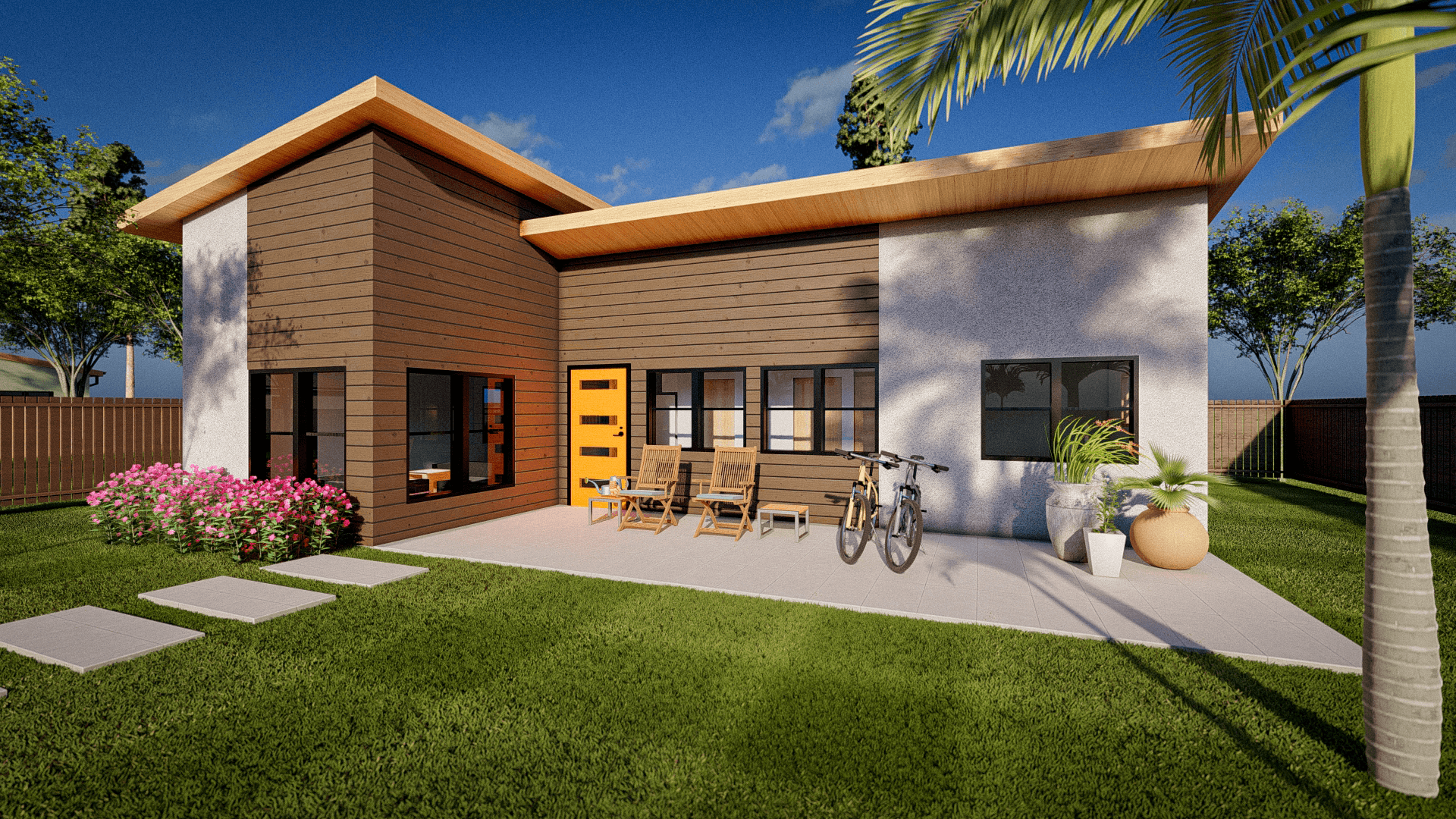 A modern architectural 3D rendering of a contemporary house with a split-level design. The left section has vertical brown wood siding and a peaked roof, while the right section has white stucco walls and horizontal brown wood accents. The house features large windows with black frames and a bright yellow front door. A concrete patio extends from the right side of the house with two wooden lounge chairs and a bicycle leaning against the wall. Pink flowering bushes line the left side of the patio, and a palm tree with green fronds stands on the right. The lawn is bright green and well-maintained. The scene is set against a bright blue sky with white clouds. A wooden fence is visible in the background. The architectural style combines modern and tropical elements with clean lines and natural materials. The lighting creates distinct shadows from the palm tree and architectural elements on the white stucco wall.