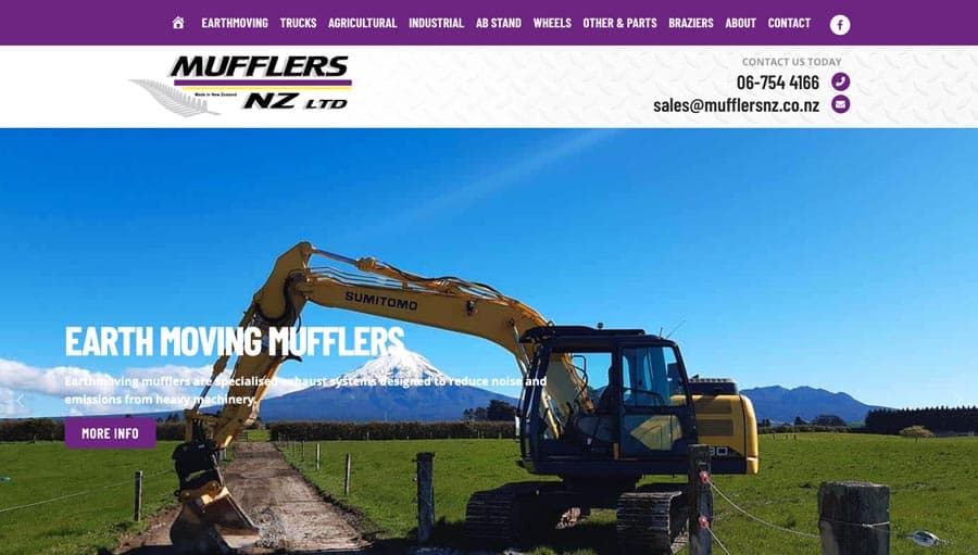 Heavy-duty earthmoving excavator operating in a field with mountains in background.