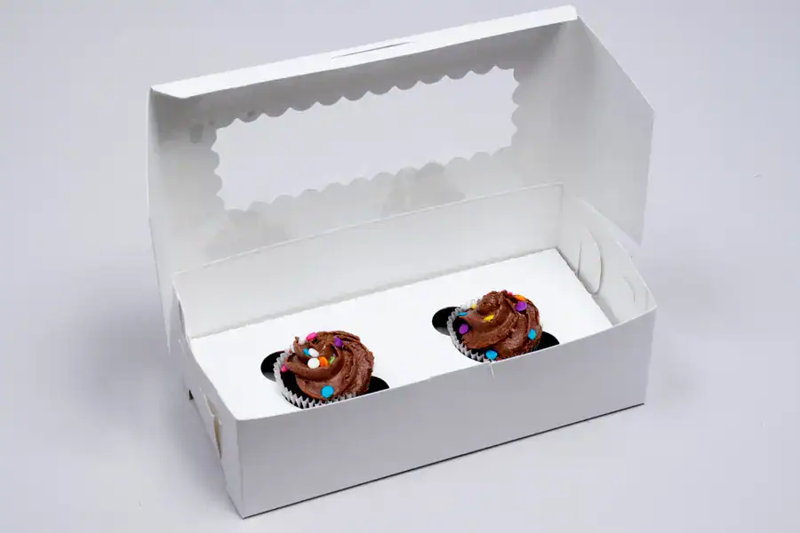 Chocolate cupcakes in a bakery box with a clear window for display.