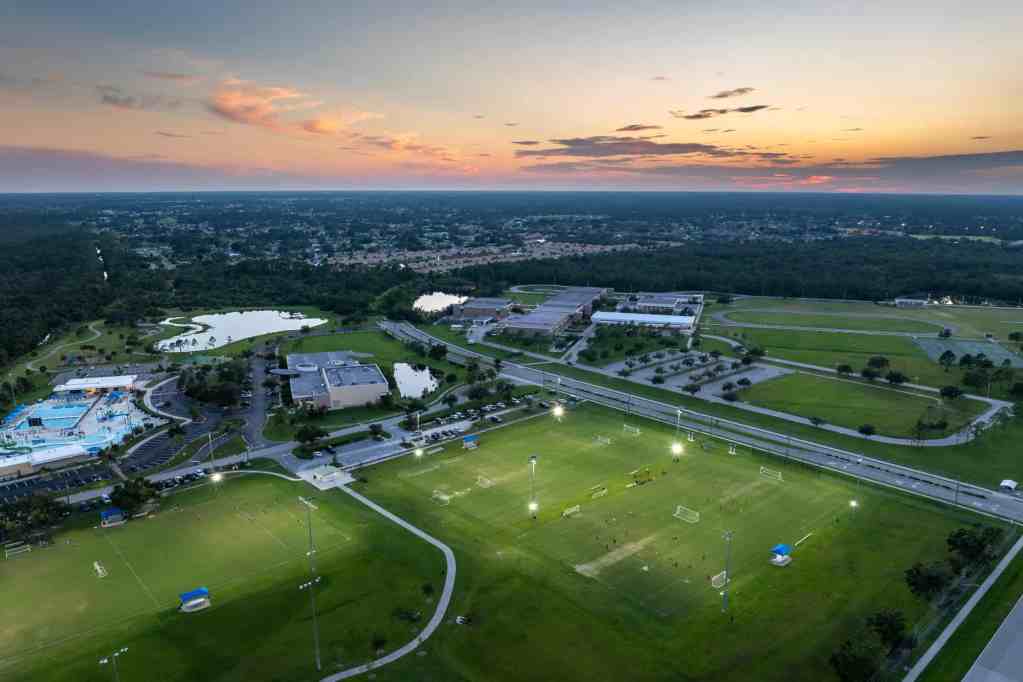 Aerial view of public sports park with people engaged in football game